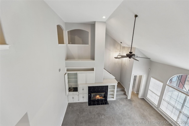 carpeted living room featuring high vaulted ceiling, a tile fireplace, and ceiling fan