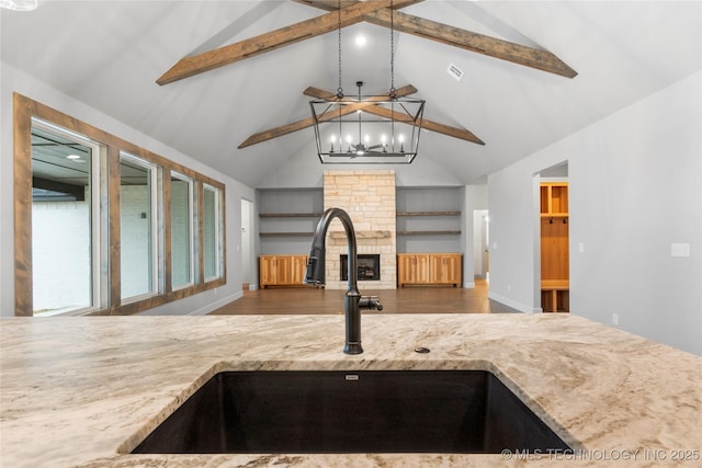 kitchen with sink, a fireplace, dark hardwood / wood-style flooring, decorative light fixtures, and beamed ceiling