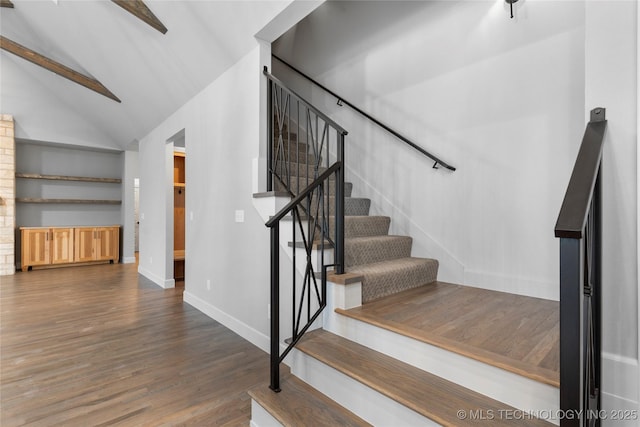 stairway with wood-type flooring and vaulted ceiling with beams