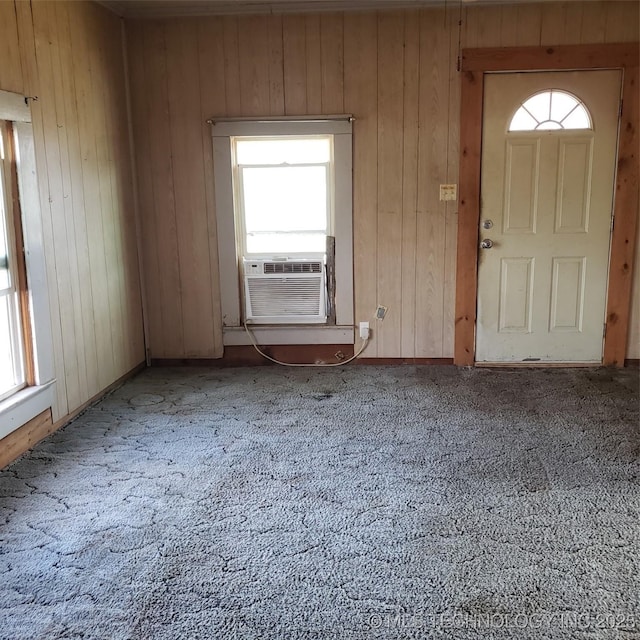 foyer entrance featuring cooling unit, plenty of natural light, and wood walls