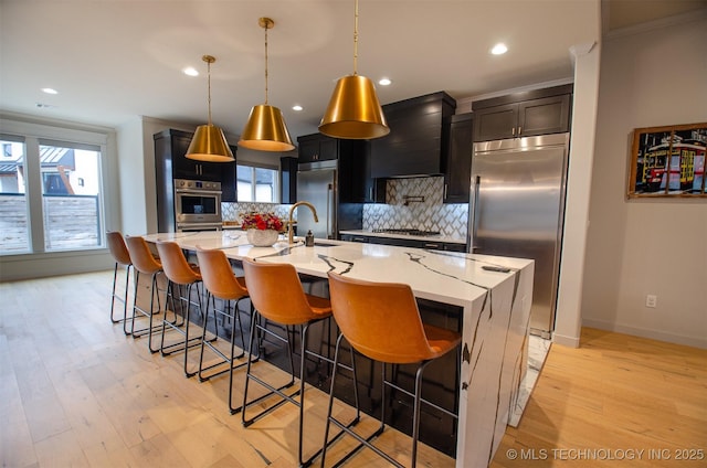 kitchen featuring appliances with stainless steel finishes, a breakfast bar, pendant lighting, decorative backsplash, and a spacious island