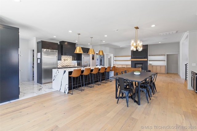 3748 E 116th St S, Tulsa, OK 74137 - dining area featuring recessed lighting, light wood-style flooring, a fireplace, and a chandelier