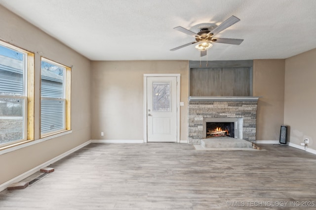 unfurnished living room featuring ceiling fan, a textured ceiling, light hardwood / wood-style floors, and a fireplace