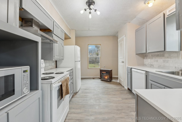 kitchen with tasteful backsplash, gray cabinetry, white appliances, a textured ceiling, and light wood-type flooring