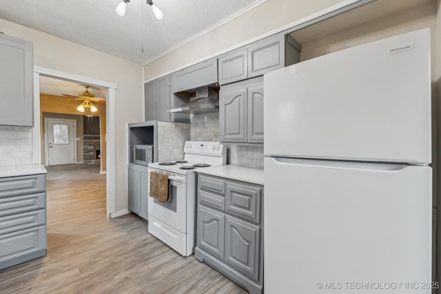 kitchen with wall chimney range hood, white appliances, gray cabinets, and ceiling fan