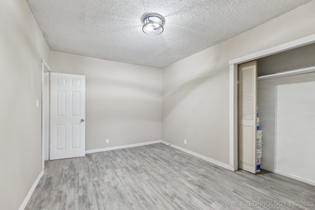 unfurnished bedroom with a closet, light hardwood / wood-style floors, and a textured ceiling