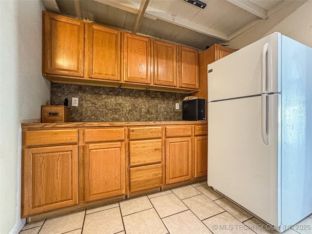 kitchen with tasteful backsplash, beamed ceiling, white fridge, and light tile patterned floors