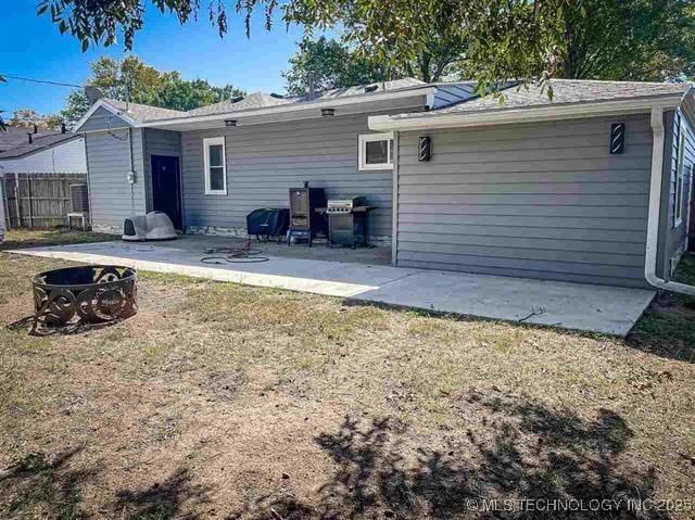 back of house with a yard, a patio area, and an outdoor fire pit