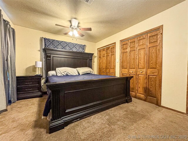 carpeted bedroom with multiple closets, a textured ceiling, and ceiling fan