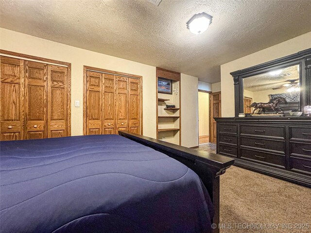 bedroom with a textured ceiling, multiple closets, and carpet flooring