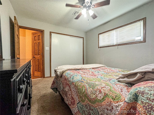 carpeted bedroom with a textured ceiling, a closet, and ceiling fan