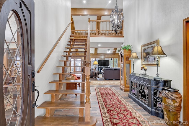 foyer entrance with ceiling fan with notable chandelier and a high ceiling