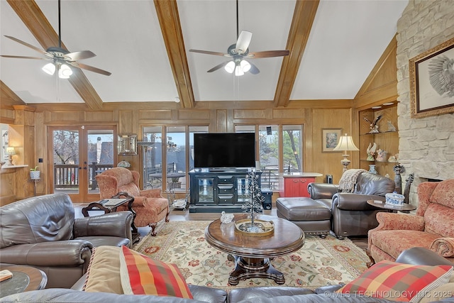 living room with ceiling fan, high vaulted ceiling, french doors, beamed ceiling, and wood walls