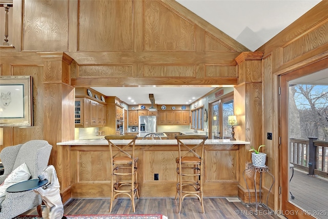 kitchen featuring lofted ceiling, dark hardwood / wood-style floors, a kitchen bar, stainless steel fridge with ice dispenser, and kitchen peninsula