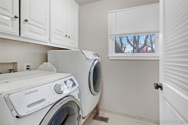 clothes washing area with cabinets and washing machine and clothes dryer