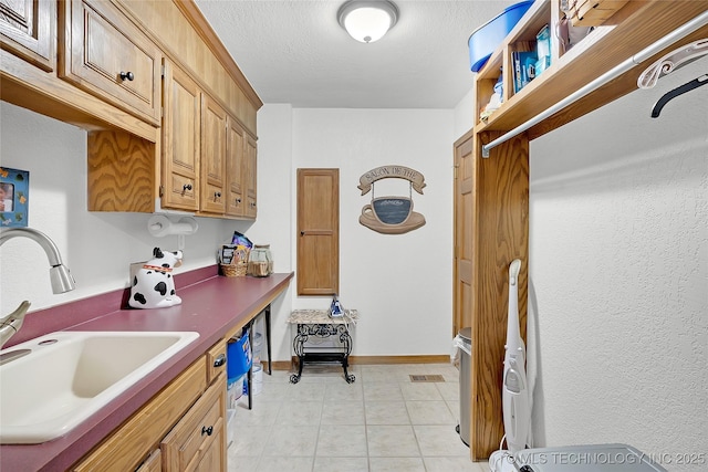 kitchen featuring sink, a textured ceiling, and light tile patterned floors