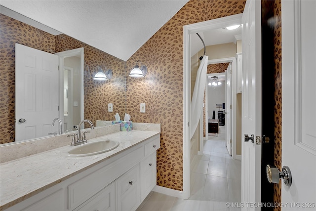 bathroom featuring vanity, vaulted ceiling, tile patterned floors, and a textured ceiling