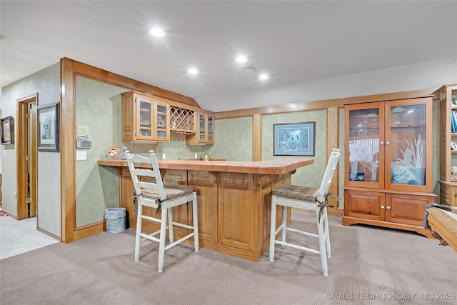 bar with light colored carpet, lofted ceiling, and tile countertops