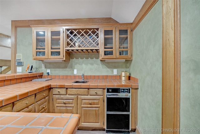 kitchen featuring vaulted ceiling, sink, tile countertops, and light brown cabinets