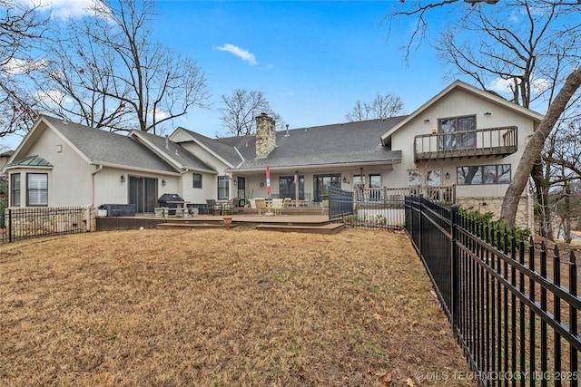 back of property with a lawn, a balcony, and a deck