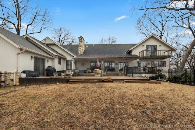 rear view of house with a balcony, a yard, and a deck