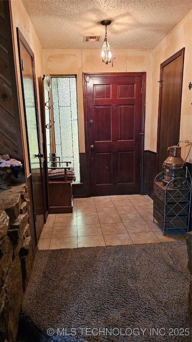 foyer entrance featuring light tile patterned floors and a textured ceiling