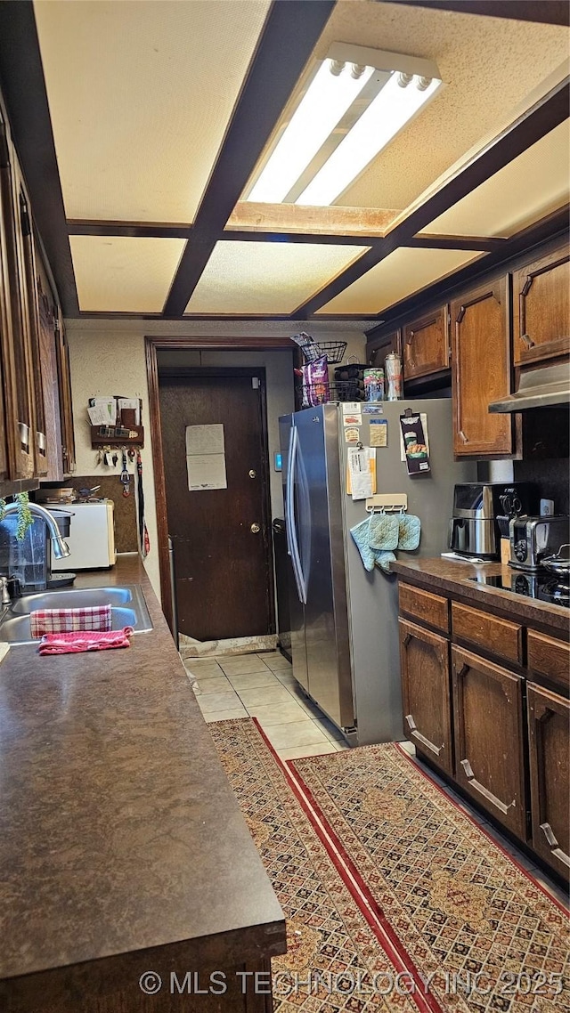 kitchen with stainless steel refrigerator with ice dispenser, dark brown cabinetry, black electric cooktop, and sink