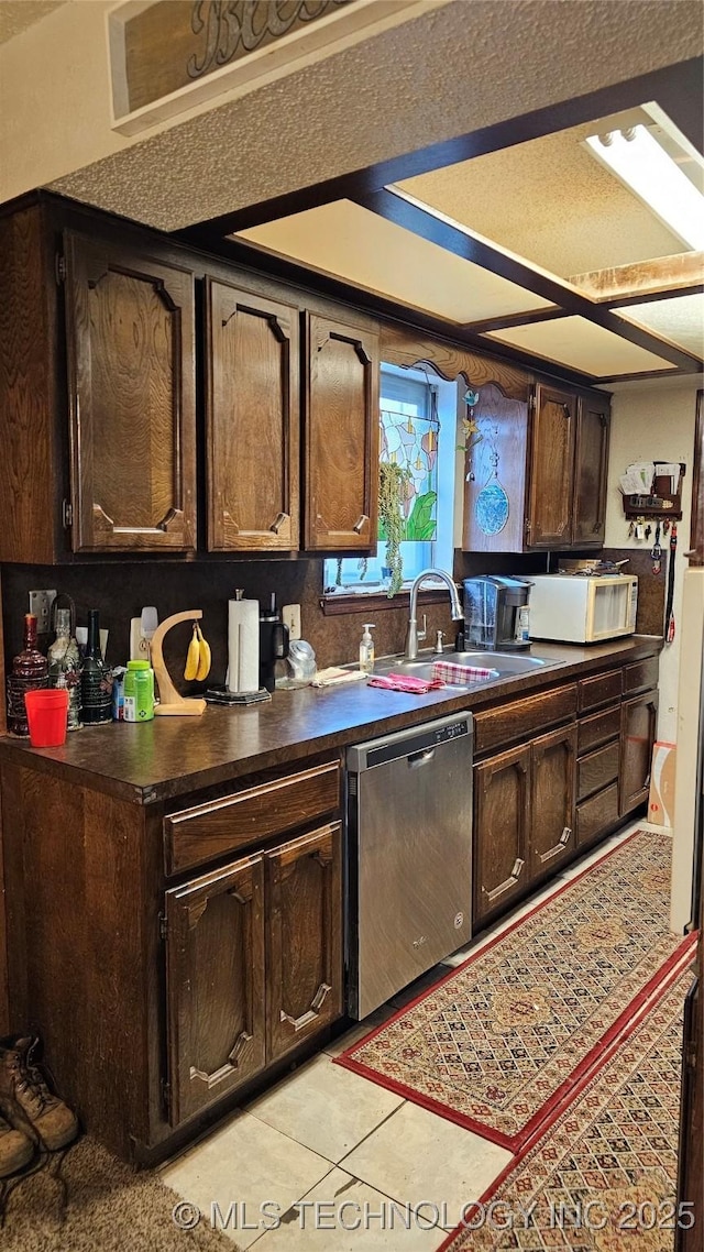 kitchen featuring dishwasher, sink, light tile patterned floors, and dark brown cabinetry