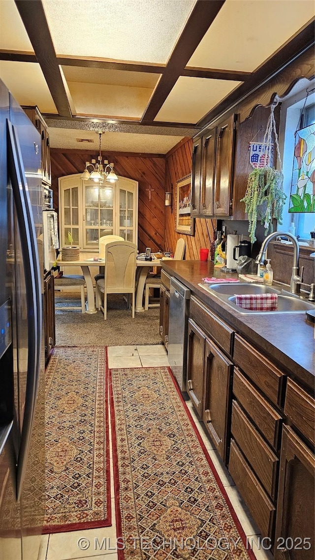 kitchen with wood walls, sink, a chandelier, dark brown cabinetry, and stainless steel appliances