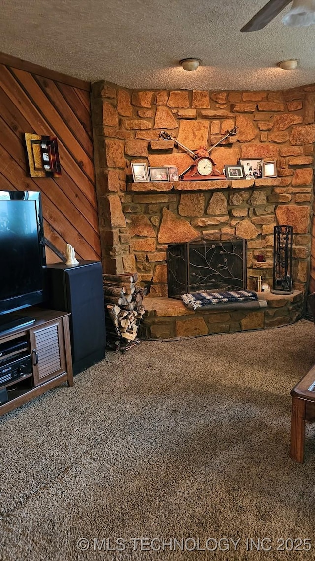 living room featuring a stone fireplace, carpet flooring, a textured ceiling, and wood walls