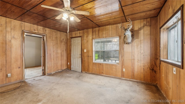 spare room with ceiling fan, wood ceiling, and wooden walls