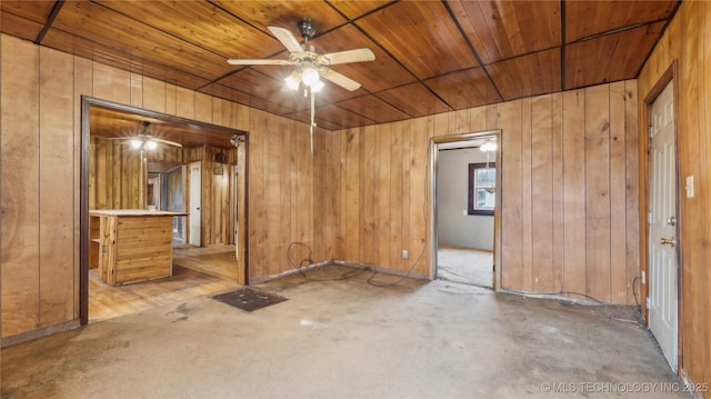 spare room featuring wood ceiling, wooden walls, and ceiling fan