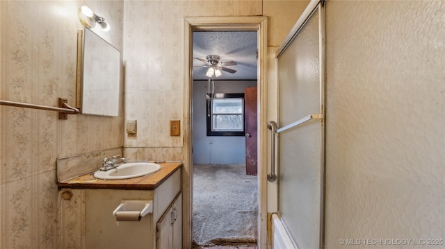 bathroom featuring vanity, ceiling fan, a textured ceiling, and a shower with shower door