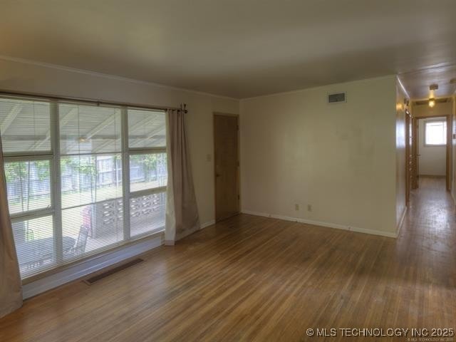 unfurnished room with visible vents, baseboards, and wood finished floors