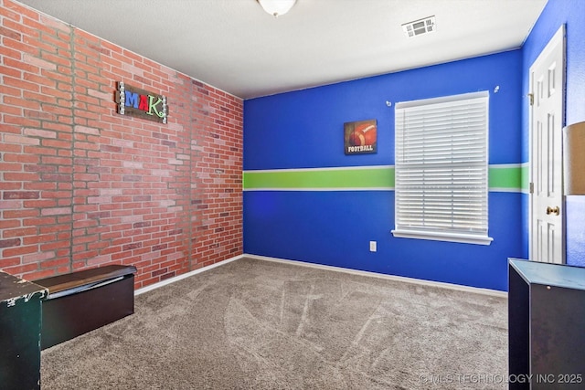 unfurnished room featuring brick wall, carpet floors, baseboards, and visible vents