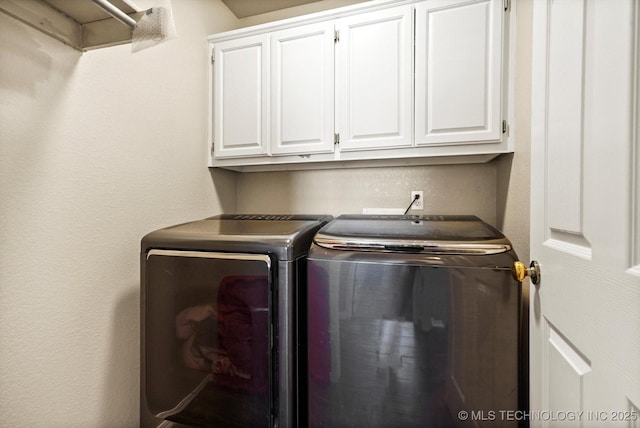 washroom with washer and dryer, cabinet space, and a textured wall
