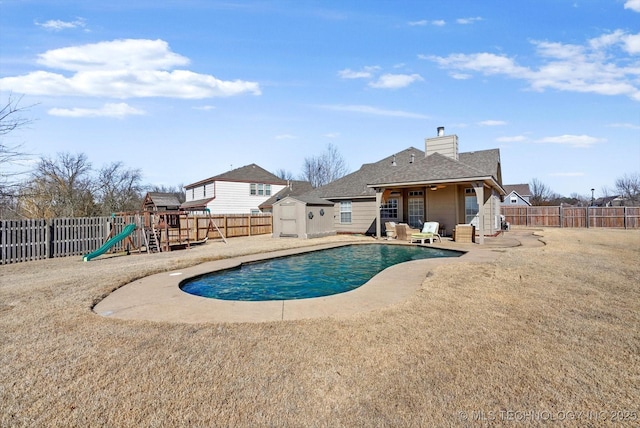 view of pool with a storage shed, a yard, a patio area, and a playground