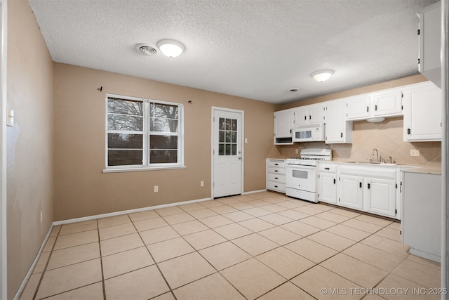 kitchen with light tile patterned flooring, sink, white cabinetry, white appliances, and decorative backsplash