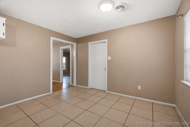 empty room featuring a textured ceiling and light tile patterned flooring