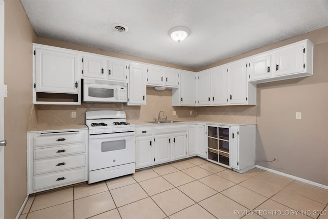 kitchen with tasteful backsplash, sink, white cabinets, and white appliances