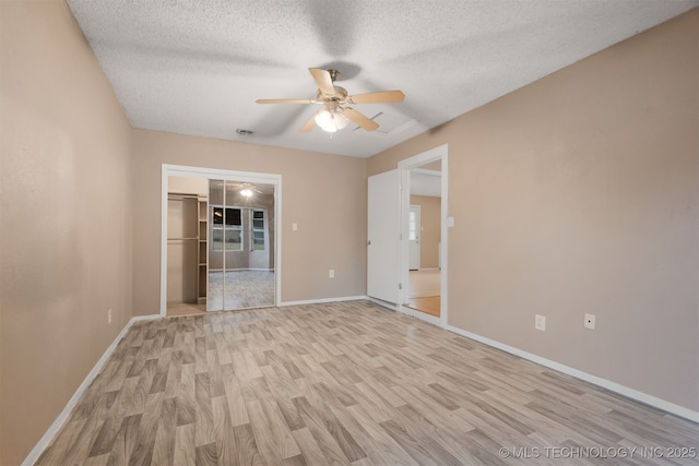 unfurnished room featuring ceiling fan, a textured ceiling, and light wood-type flooring