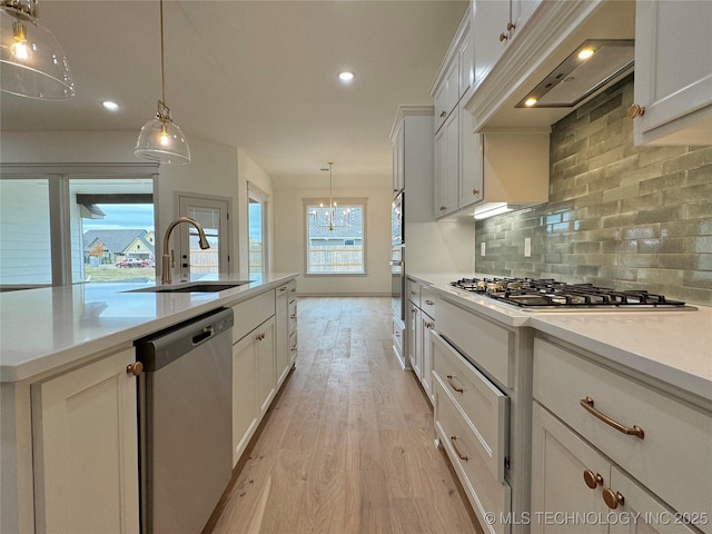 kitchen with white cabinetry, appliances with stainless steel finishes, custom range hood, and pendant lighting