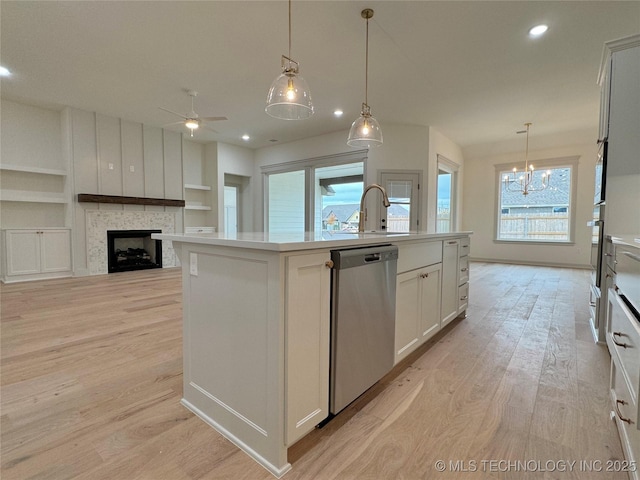 kitchen featuring pendant lighting, light hardwood / wood-style flooring, stainless steel appliances, and a center island with sink