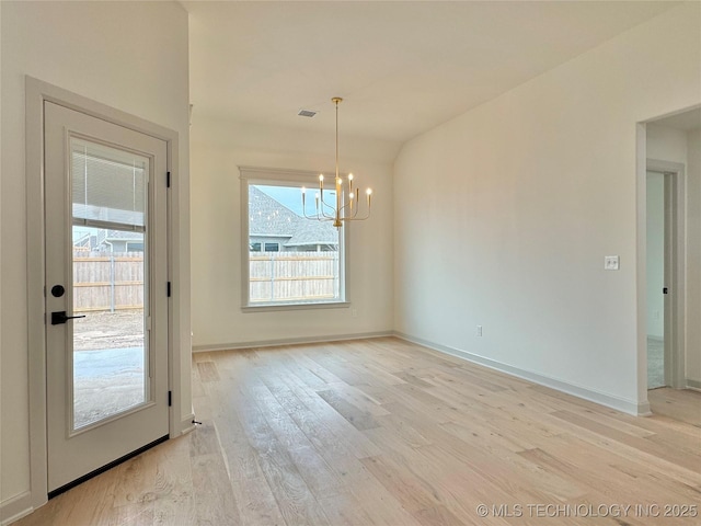 unfurnished dining area with an inviting chandelier and light hardwood / wood-style flooring