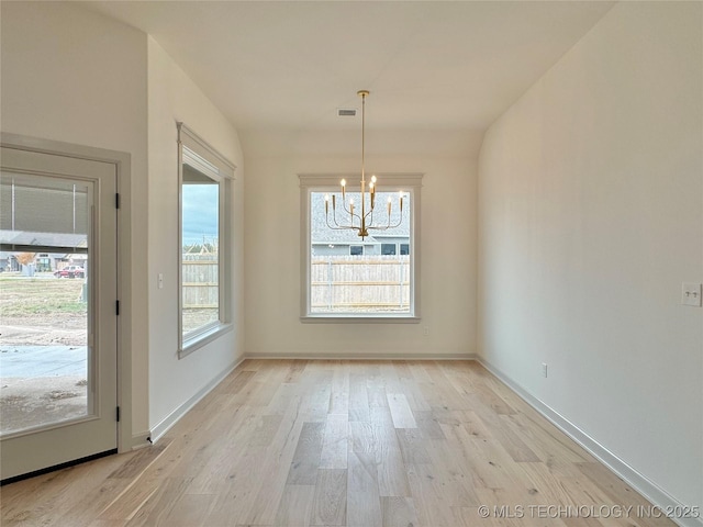 unfurnished dining area with light hardwood / wood-style flooring and a notable chandelier