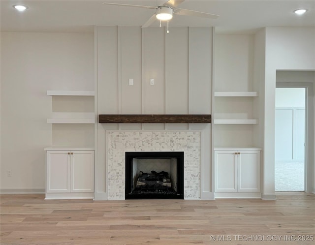 details featuring hardwood / wood-style floors, built in shelves, a tile fireplace, and ceiling fan