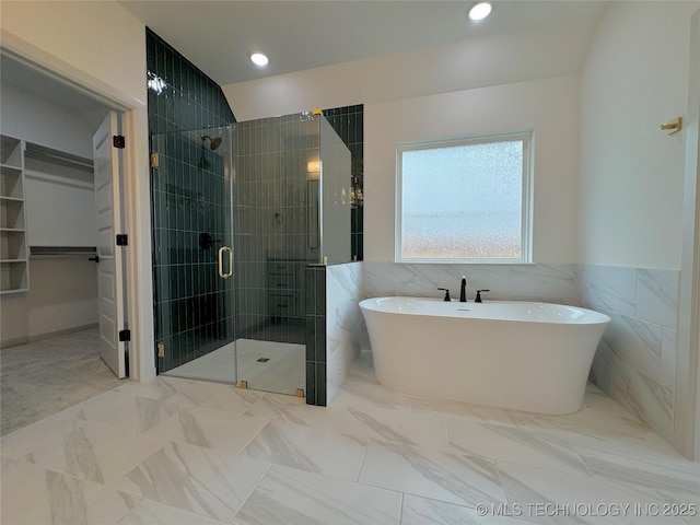 bathroom with shower with separate bathtub and tile walls