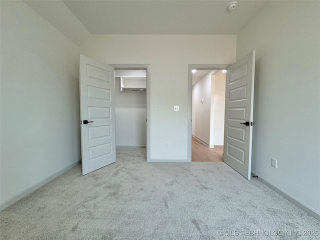 unfurnished bedroom featuring a walk in closet and light carpet