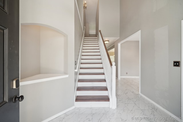 staircase featuring baseboards and marble finish floor