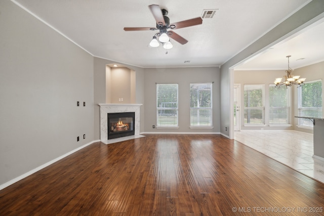 unfurnished living room with plenty of natural light, ceiling fan with notable chandelier, a premium fireplace, and visible vents
